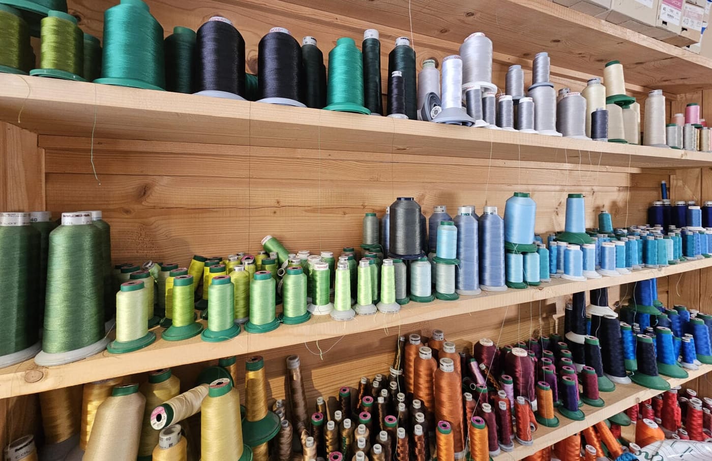 Mur de bobines de fils de broderie de toutes les couleurs à l'atelier